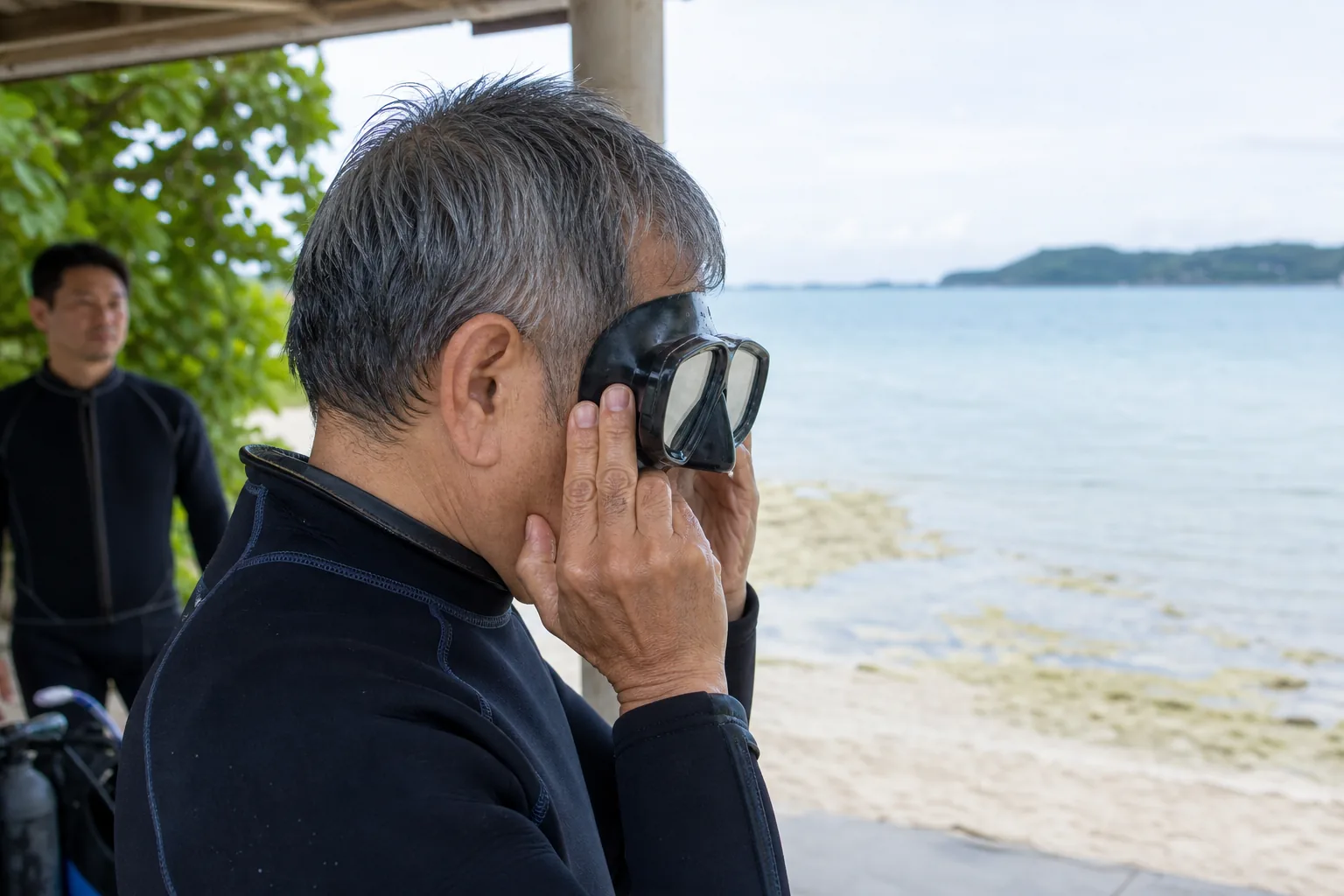 海へ入る前に2眼マスクを顔へ当ててフィットを確かめる60代男性
